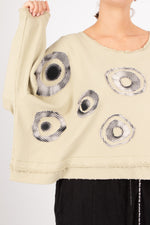 Beige sweater with circular patterns worn by a person on a light gray background